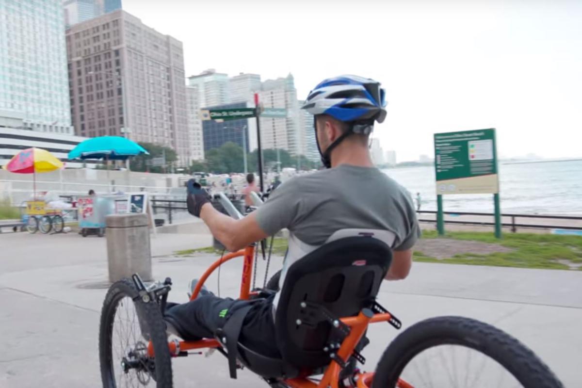 Brad the Bullet Baker riding a hand cycle on a beach in chicago
