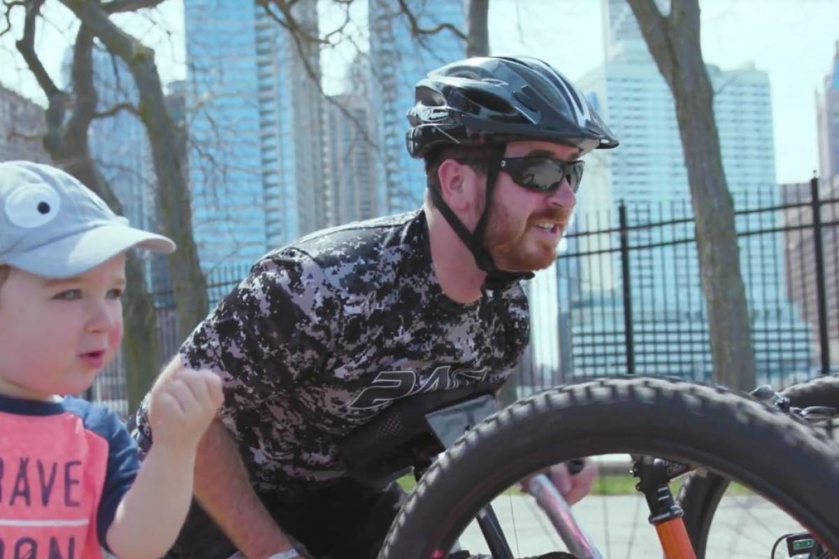 colton on a hand-cycle riding in downtown Chicago with is young son