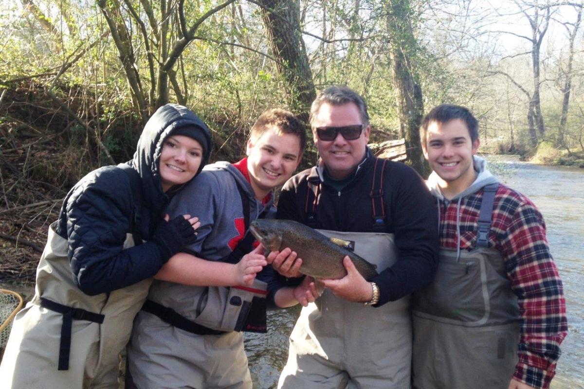 Scott and family in fishing gear holding a fish