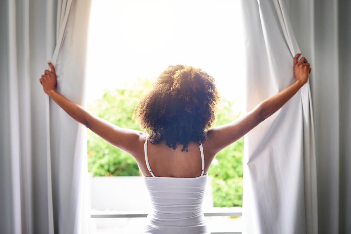 Woman opening curtains in the morning