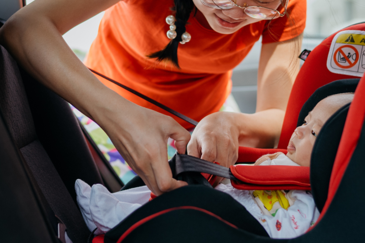 Mom buckling child into car seat