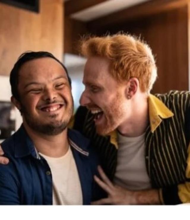 a young adult man with a developmental disabilities and a young white man with red hair giving him a hug. The man with red hair is a DSP