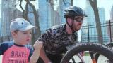 colton on a hand-cycle riding in downtown Chicago with is young son