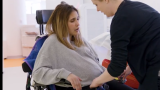 Adriana pictured in a wheelchair with a physical therapist