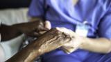 Nurse holds hands of patient