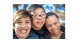 Three individuals with intellectual and/or developmental disabilities are smiling into the camera.