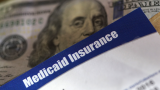 This is an image of a close-up of a Medicaid insurance card over a one hundred dollar bill.