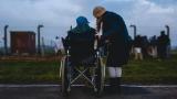 This is a picture of a person in a wheelchair and their family member looking out to a group of people standing in a field.