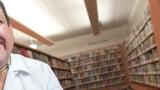 Latino man with big smile in front of shelves of books