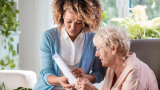 white woman senior with young black woman reading a document together