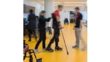 a blurred photo of a person with leg braces practicing walking with clinicans in a hospital setting