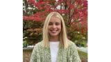 White woman with shoulder length blonde hair wearing a green sweater outside