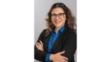 woman in suit with shoulder length brown hair and glasses