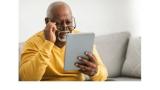 a photo of an older Black man in a yellow sweater looking at a digital tablet