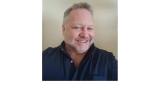 color photo of Bob Sattler, a middle aged white mad with a grey beard and grey hair wearing a black button down shirt