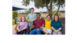 color photo of several people gathered on a park bench