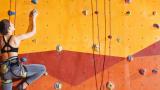 woman scales climbing wall