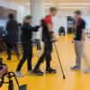 photo of a person walking with a cane being assisted by two therapists